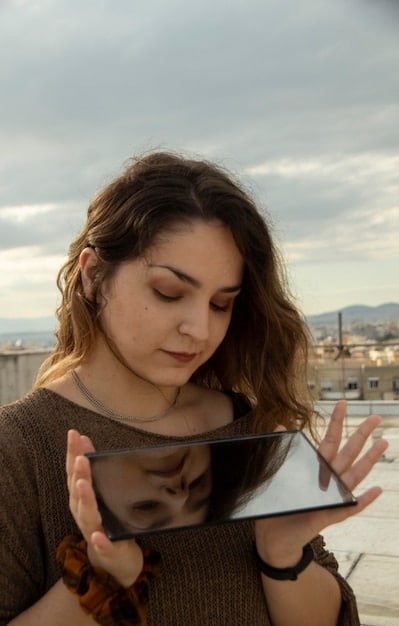 A close-up shot of a young woman in Mexico using a tablet, with a blurred background showcasing a modern office setting. The tablet displays information related to the Jóvenes Construyendo el Futuro program, emphasizing the ease of access to information and resources. Light should be bright and optimistic.