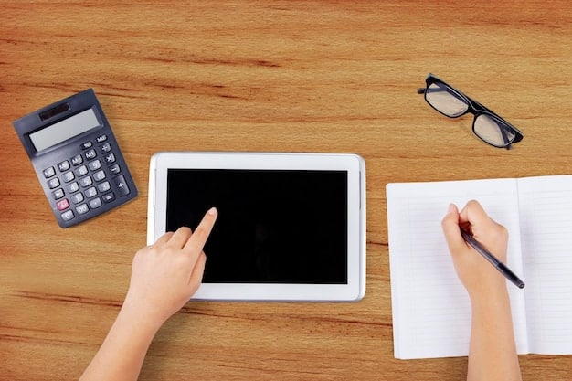 Top-down view of a person using a calculator and writing in a notebook at a wooden desk. There are several financial documents and a cup of coffee on the desk, creating a workspace focused on budgeting and financial planning.