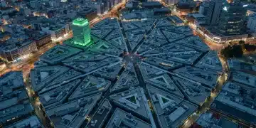 Vista aérea de una compleja ciudad moderna al anochecer con un sutil resplandor verde, simbolizando la intrincada estructura del Sistema de Ahorro para el Retiro (SAR) en México.
