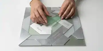 Manos de una persona ensamblando un rompecabezas geométrico de acrílico verde y metal, simbolizando el ecosistema financiero mexicano de ahorro, crédito y programas sociales sobre un escritorio blanco.
